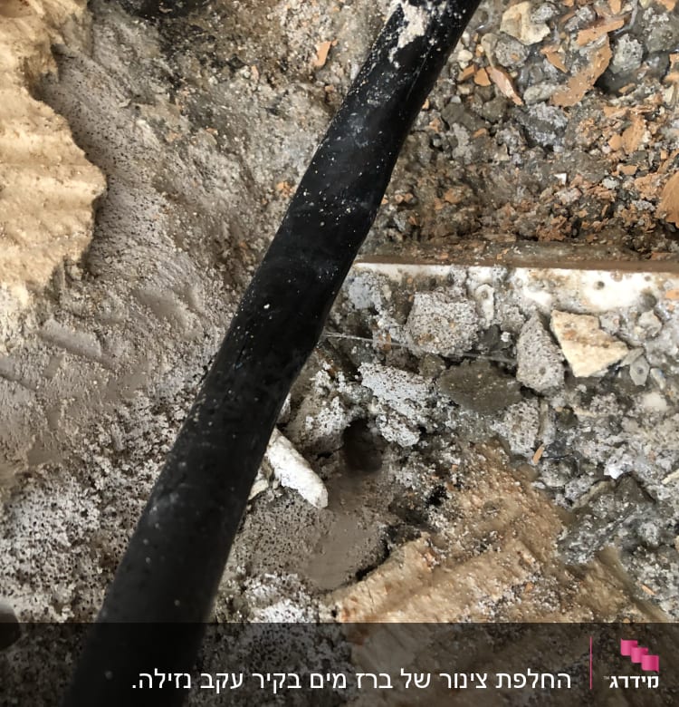 צינור שחור על רקע של אבנים וחול